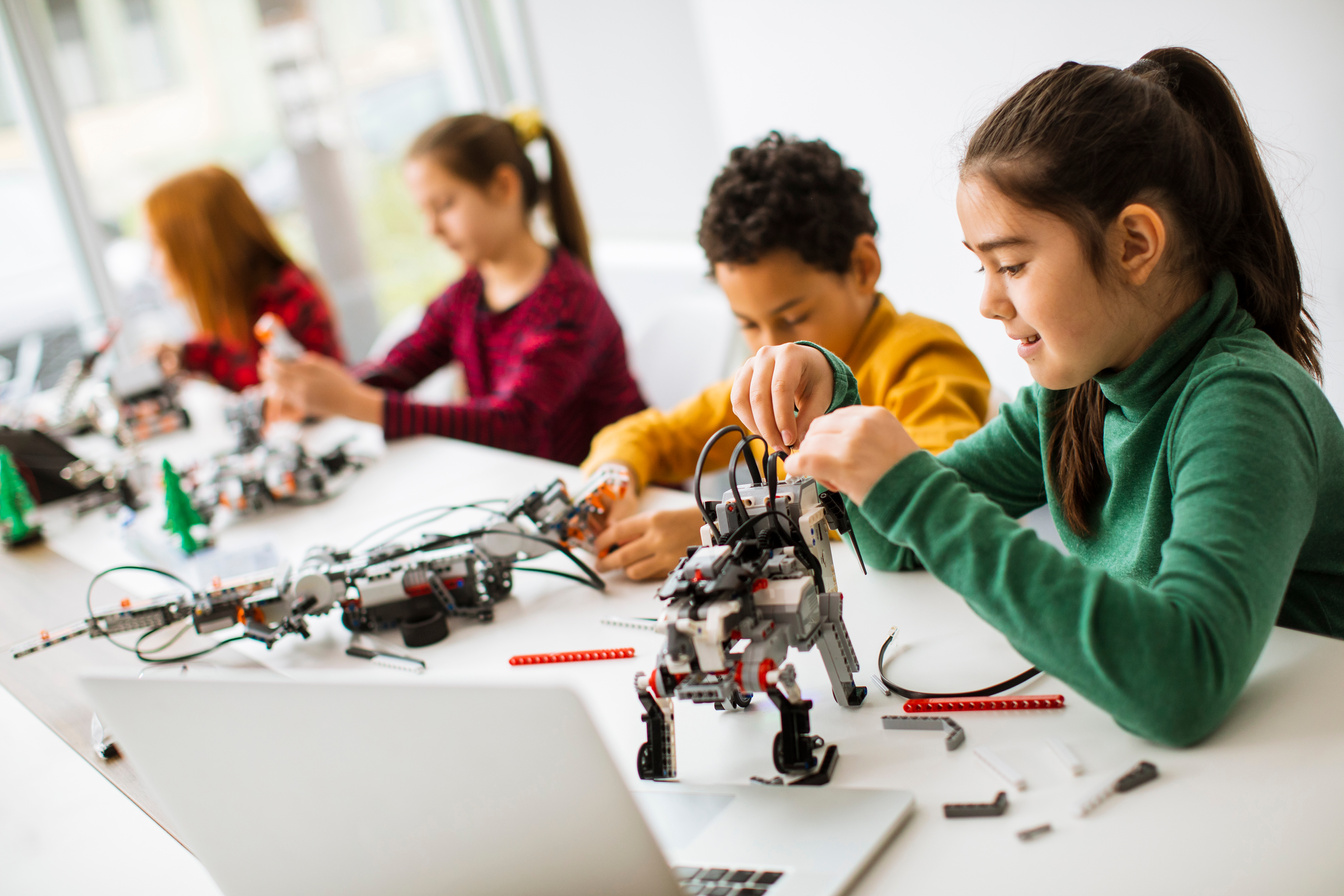 Happy kids programming electric toys and robots at robotics classroom